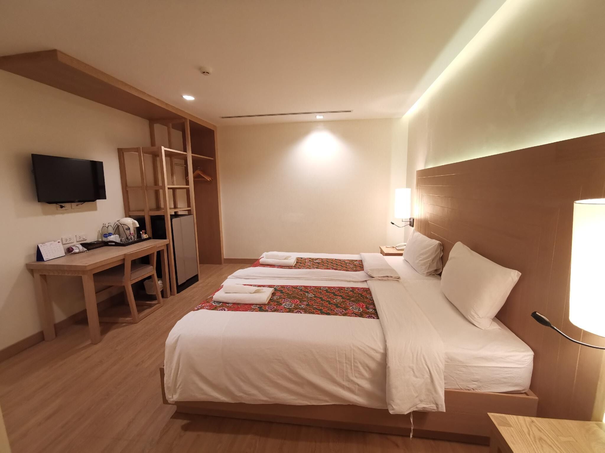 A hotel room with a bed, a desk, a television, and a wardrobe.