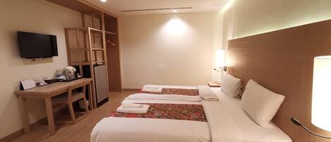 A hotel room with a bed, a desk, a television, and a wardrobe.
