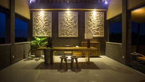 A modern kitchen with a long countertop, two stools, and decorative wall panels. - Manyi Village (Ubud)