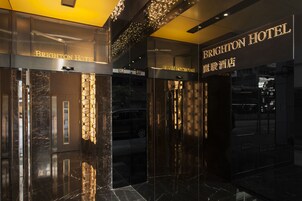 La entrada del Hotel Brighton con puertas de cristal y señalización iluminada.