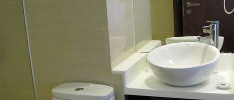 A modern bathroom with a white toilet, a large white sink, and a wooden door.