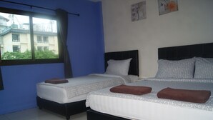 Habitación de hotel con dos camas, cada una con ropa de cama estampada y toallas marrones.
