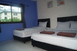 Habitación de hotel con dos camas, cada una con ropa de cama estampada y toallas marrones.