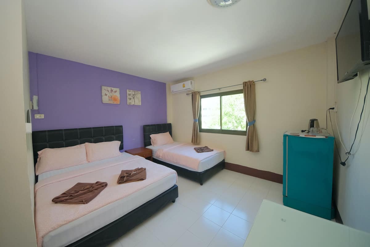 A hotel room with two beds, a TV, and an air conditioning unit.