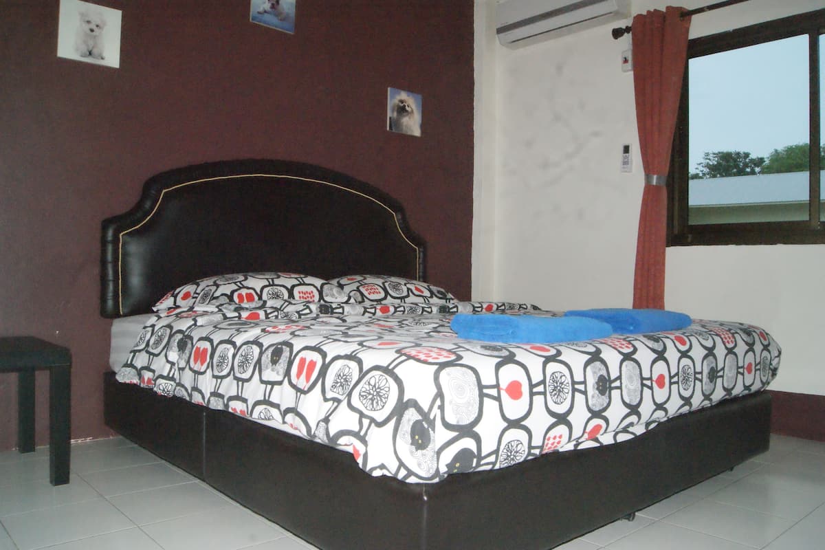 A bedroom with a bed, a nightstand, and a window with curtains.