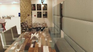 Una sala de conferencias moderna con una mesa de vidrio, asientos acolchados y una amplia pantalla de televisión.
