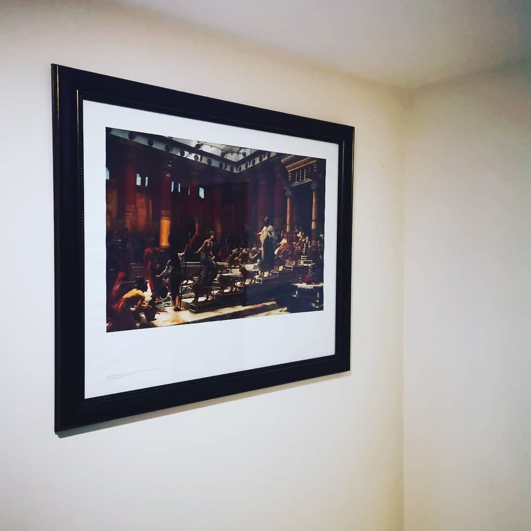 Ett inramat konstverk som föreställer en historisk scen med flera personer och arkitektoniska detaljer.