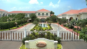A gated property with a central fountain, manicured gardens, and a sign reading "The Palms Town & Country Club". - The Palms - Town & Country Club (Gurugram)