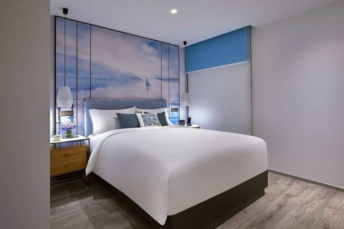 A modern bedroom with a large bed, bedside tables, and a wall-mounted artwork.