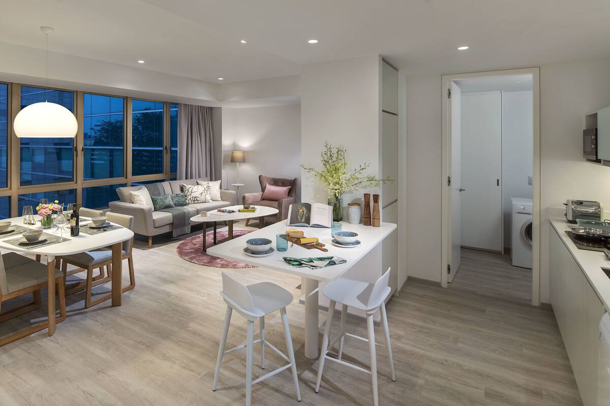 A modern living room with a dining area, large windows, and a kitchen.