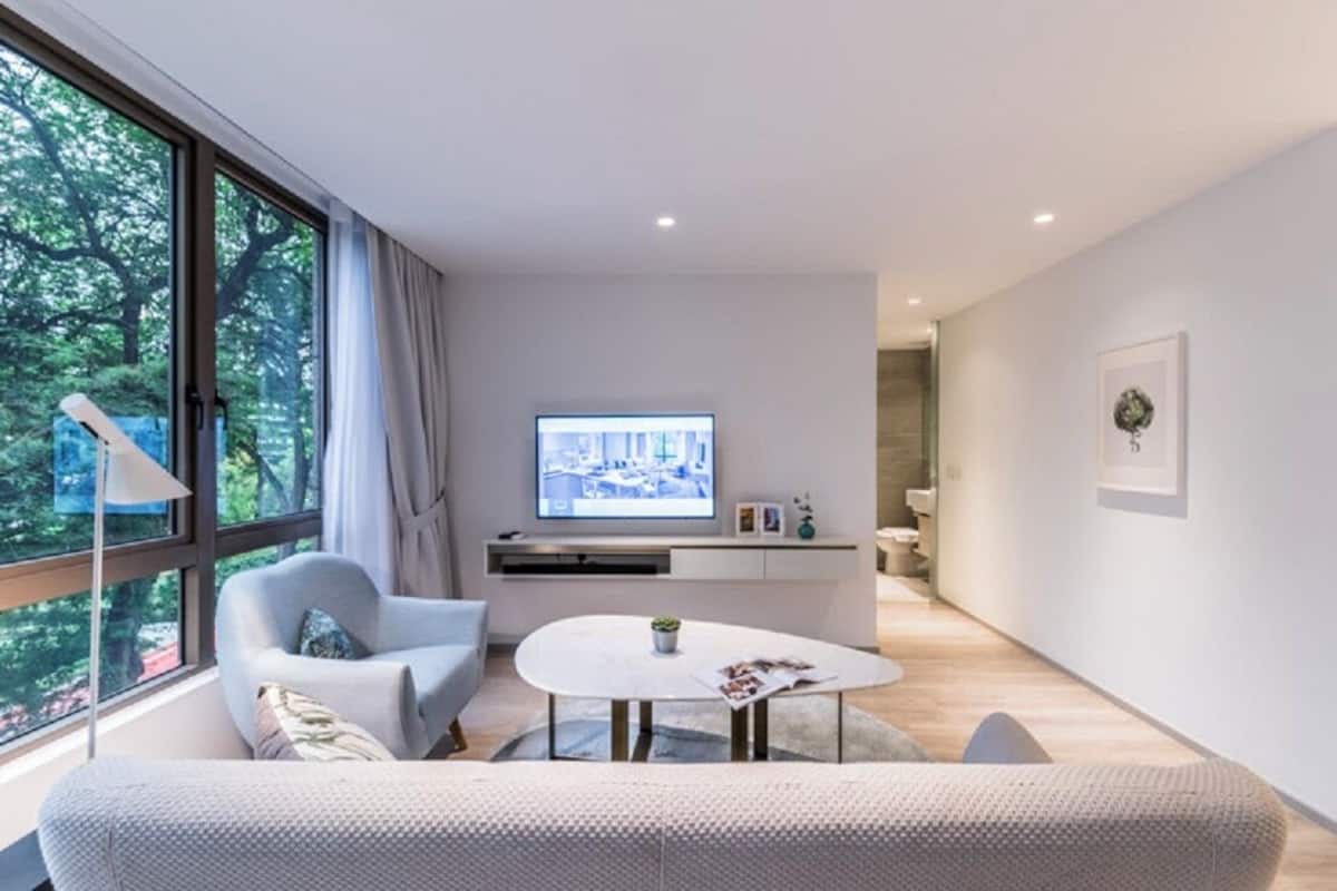 A modern living room with a large window, a flat-screen TV, a sofa, a coffee table, and a minimalist design.