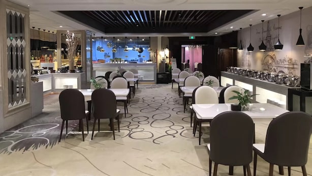A modern restaurant with a bar area, multiple dining tables, and chairs. - Sun Moon Lake Hotel (Dalian)