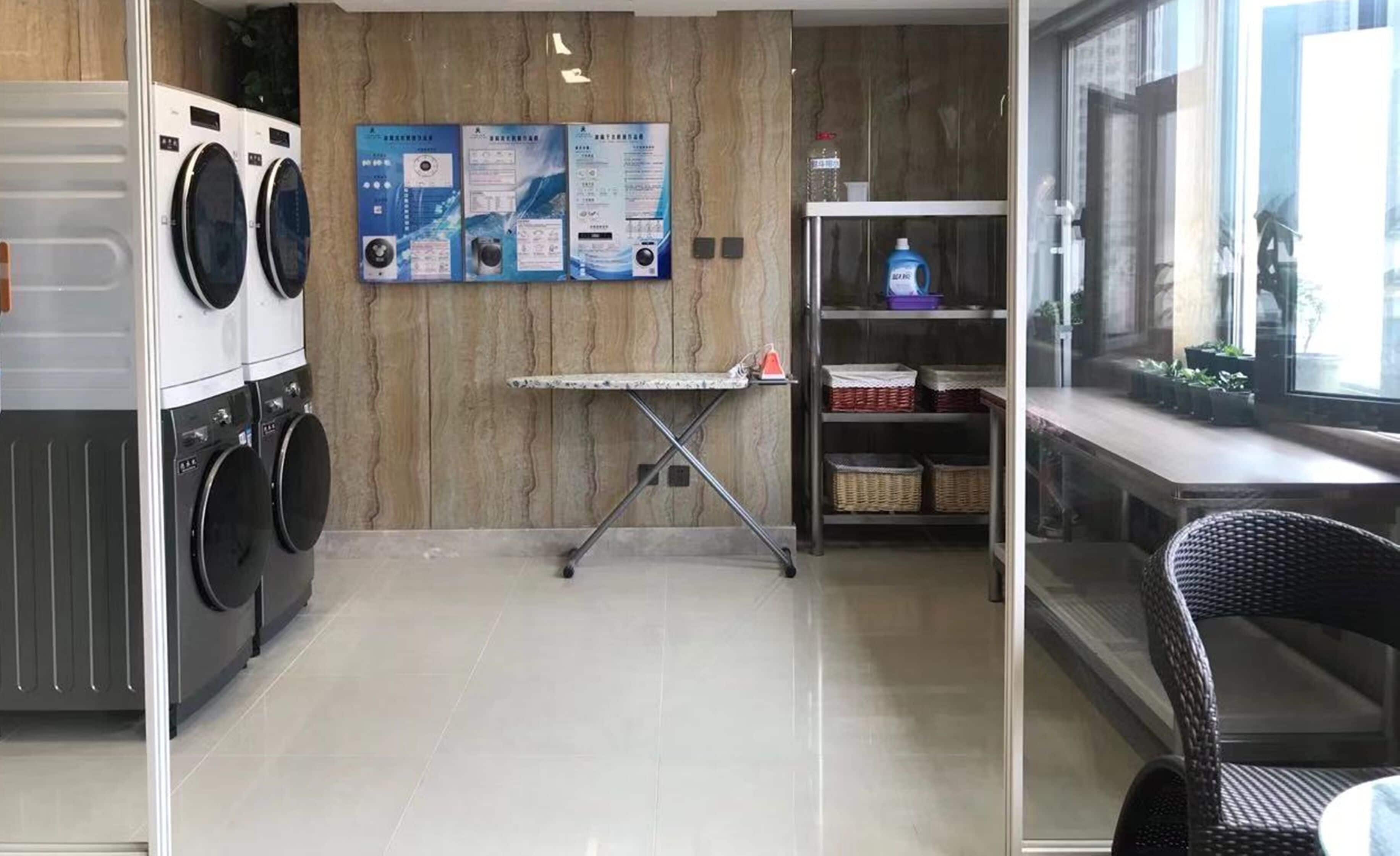 A laundry room with two washing machines, a drying rack, and a shelf with baskets.