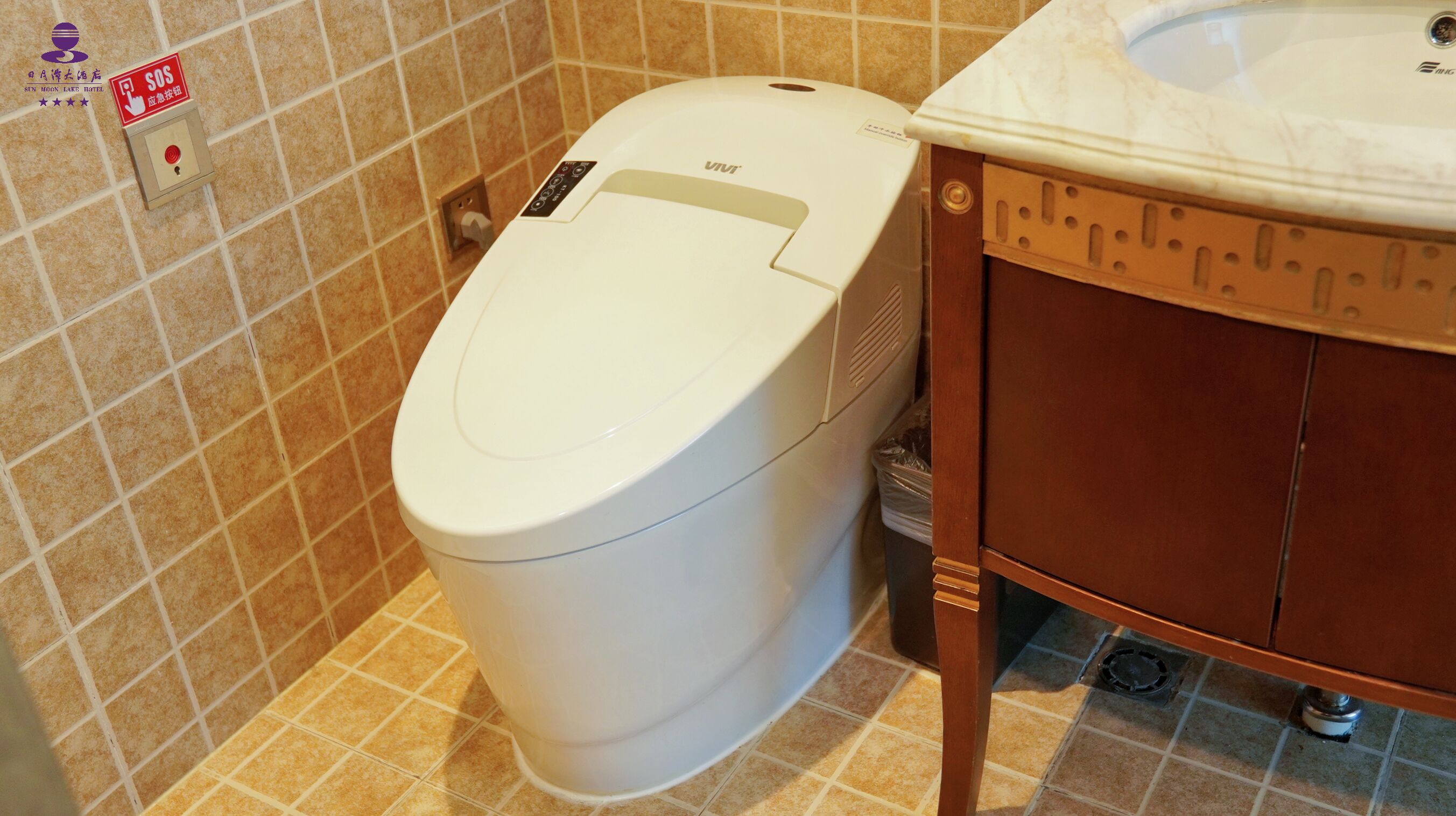 A white toilet with a control panel and a red emergency button.