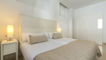 Een moderne hotelkamer met een groot bed, twee nachtkastjes met lampen en een raam.
