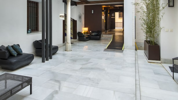 A spacious courtyard with a central seating area, a large potted plant, and a modern staircase leading to an upper level. - tuAnfitrion Elvira Suites (Granada)