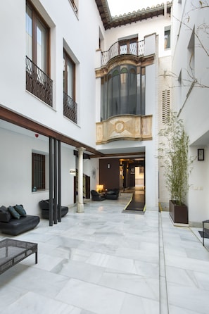 Un patio amplio con una zona de estar central, una planta grande en maceta y un diseño arquitectónico moderno.