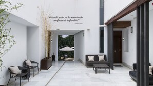 A modern interior with a central open space, a seating area with a sofa and chairs, and a decorative wall piece. - tuAnfitrion Elvira Suites (Granada)