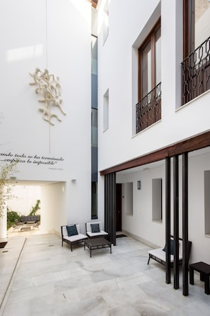 Un edificio moderno con un patio, mesas al aire libre y una cita en la pared.