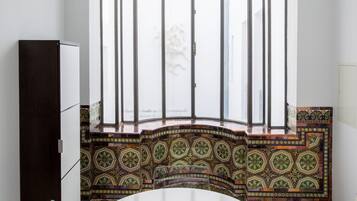 A dining area with a round table, clear chairs, a decorative partition, and a view through a window with a patterned design.