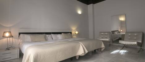 A bedroom with a large bed, bedside lamps, a chair, and a mirror.
