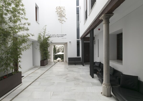 A modern interior with a central corridor, seating areas, and a decorative wall piece.