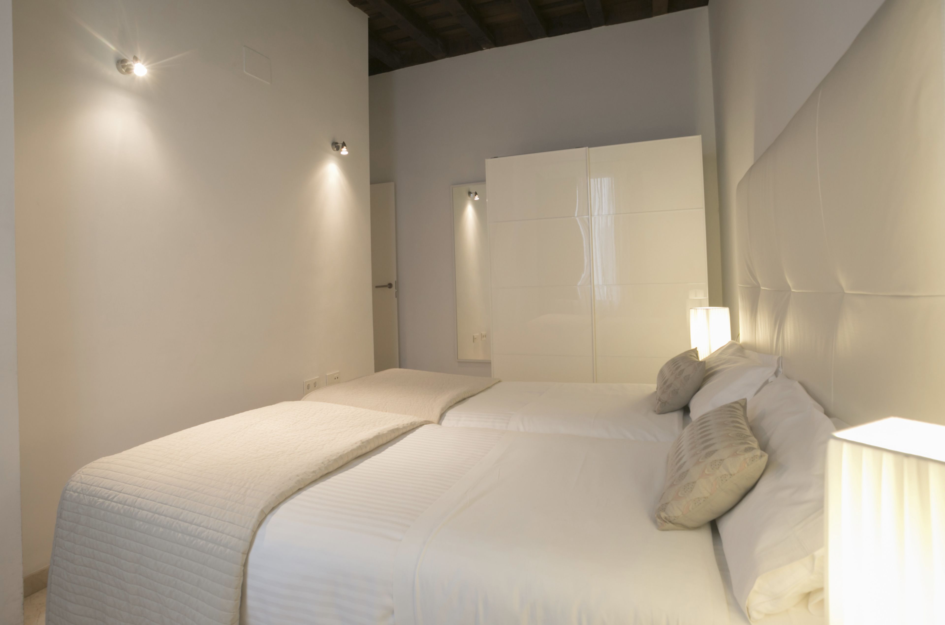 Een slaapkamer met twee bedden, een grote spiegel en een bedlampje.