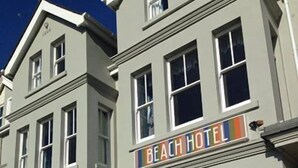 Un edificio con un letrero que dice "BEACH HOTEL" y sillones Adirondack verdes afuera.