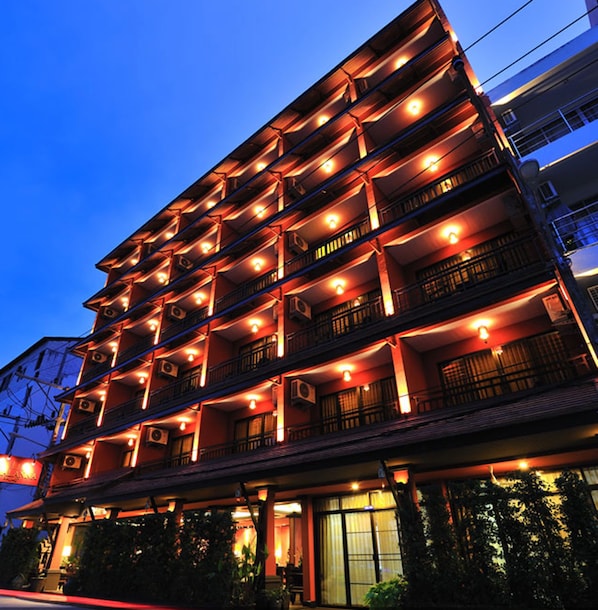 A multi-story hotel with balconies and air conditioning units, featuring a traditional architectural style.
