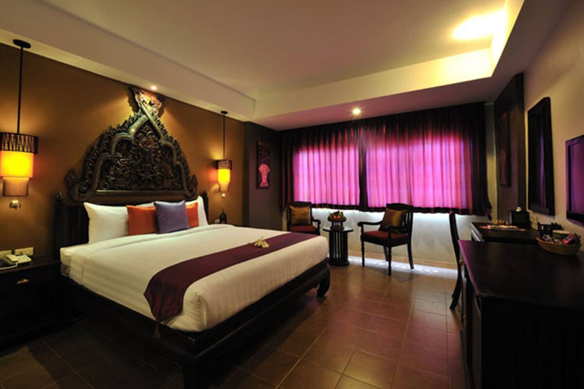 Ein Hotelzimmer mit einem großen Bett, einem Schreibtisch, einem Sessel und einem kleinen Tisch.