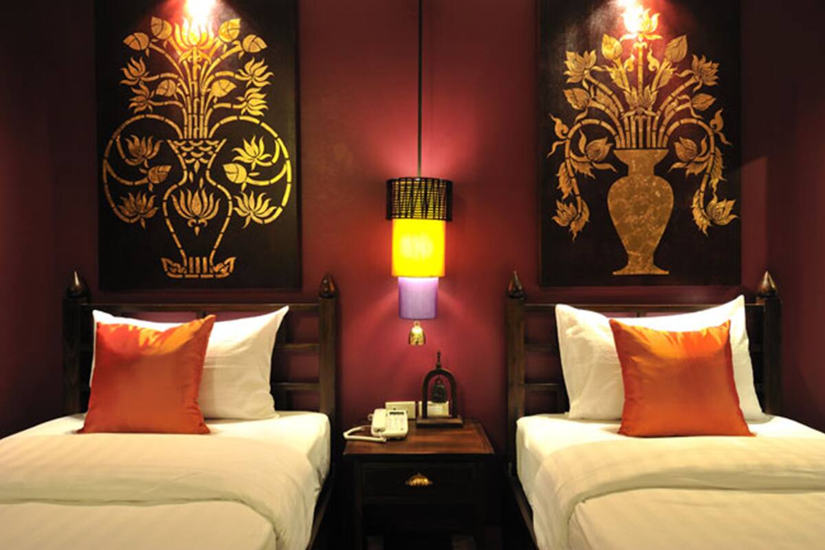 Ein Hotelzimmer mit zwei Betten, einem Nachttisch mit Lampe und Bildern an den Wänden.