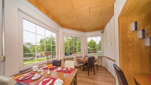 Een eetruimte met een houten tafel voor vier personen, grote ramen en uitzicht op het omliggende landschap.