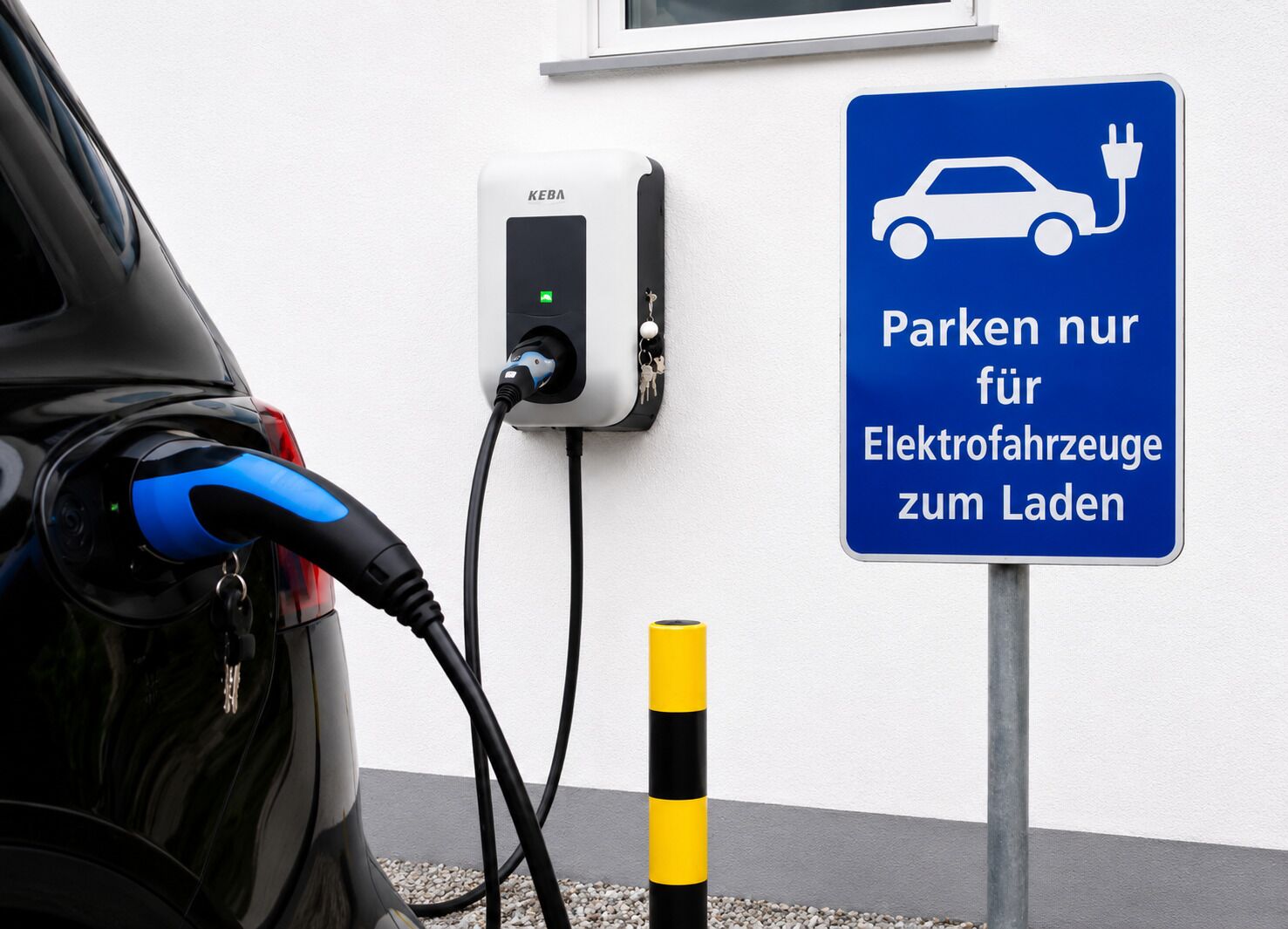 A car charging at a station with a sign indicating parking is for electric vehicles only.