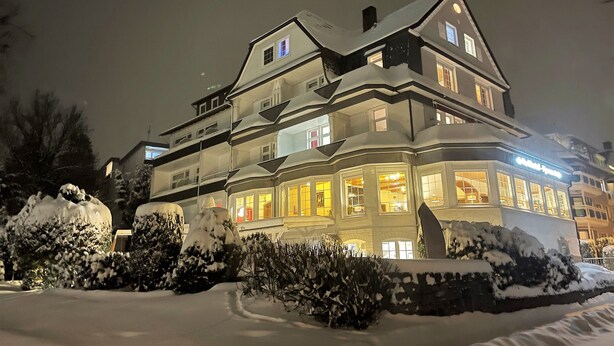 Een meerlaags hotel met een opvallende hoftopgang, grote ramen en besneeuwde omgeving.