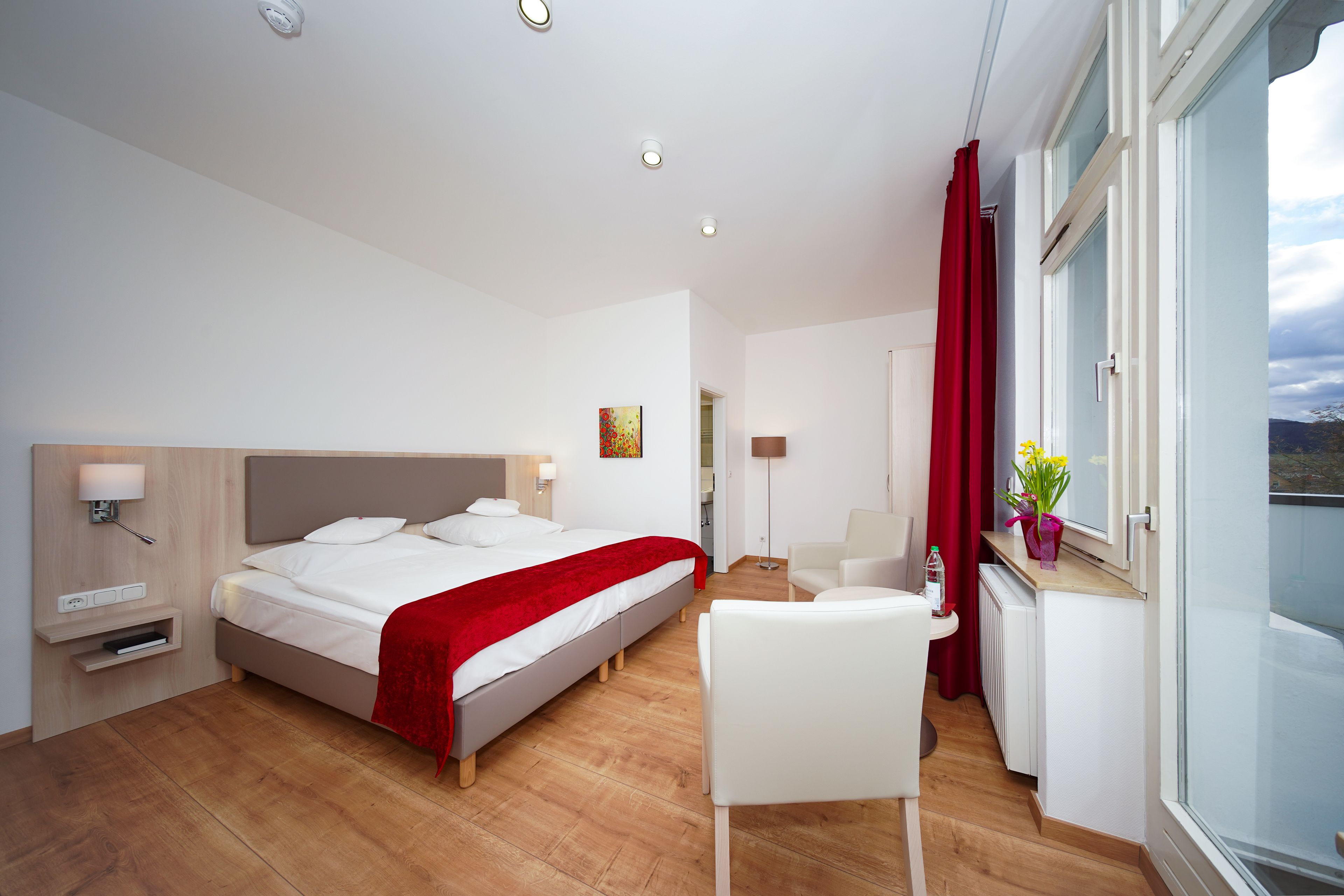 Une chambre d’hôtel moderne, dotée d’un grand lit, d’un bureau, d’une chaise et offrant une vue sur l’extérieur.