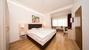 Een moderne hotelkamer met een groot bed, nachtkastjes, een bureau en een televisie.
