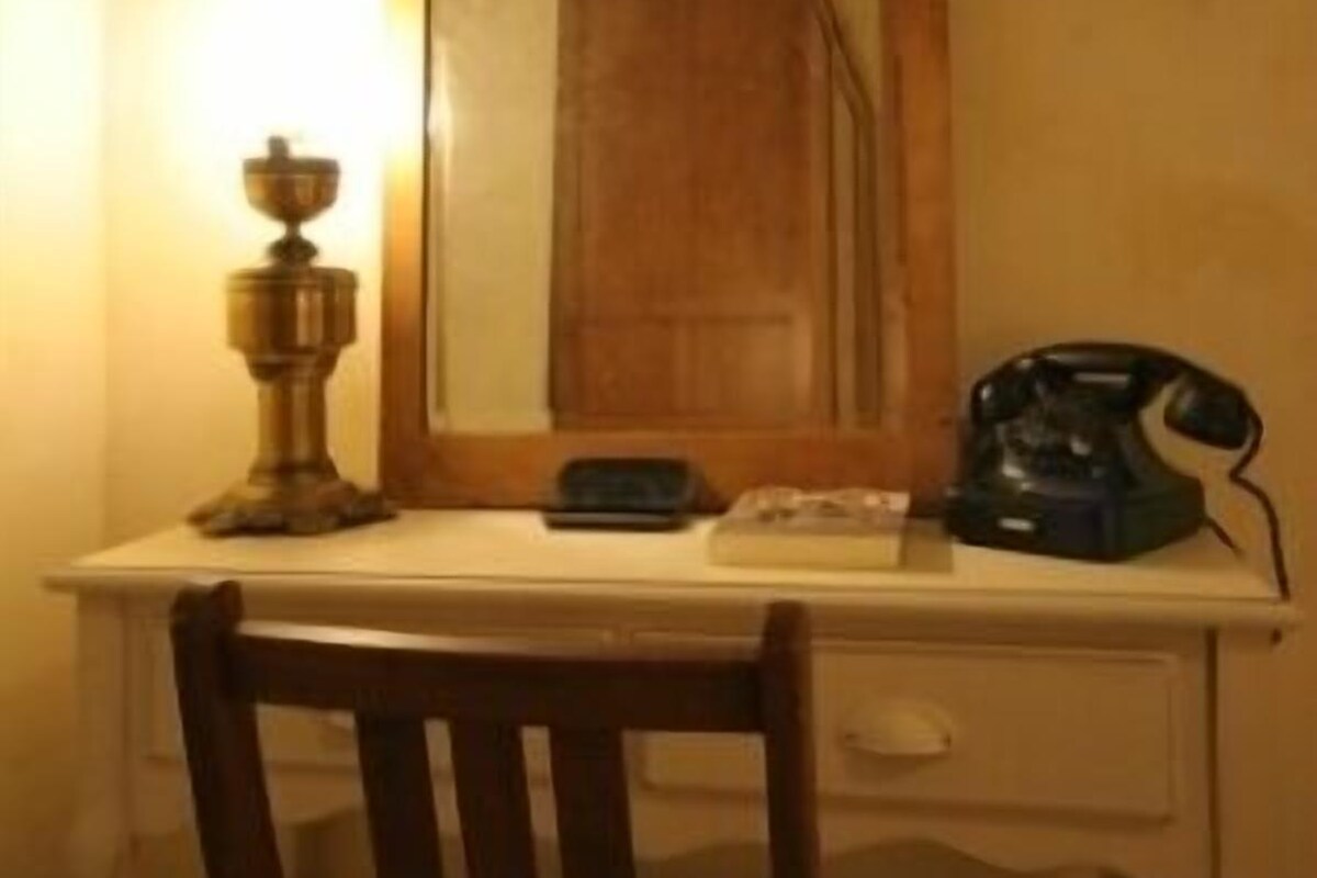 A desk with a mirror, a telephone, and a lamp.