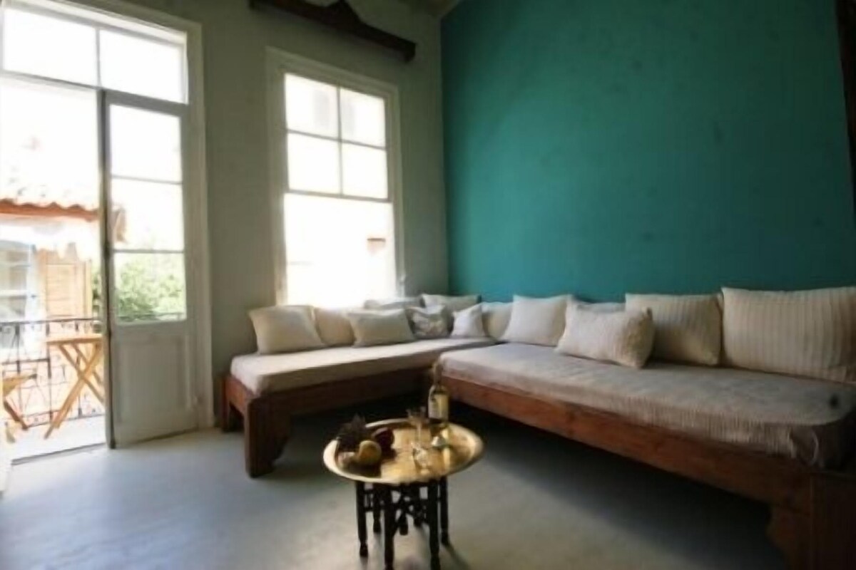 A cozy living room with a sofa, a small round table, and a view of the outside.