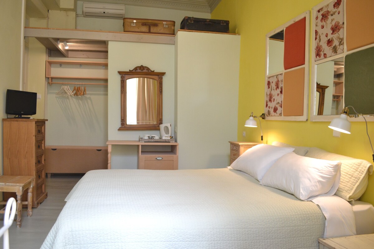 A bedroom with a bed, bedside table, dresser, television, and a mirror.