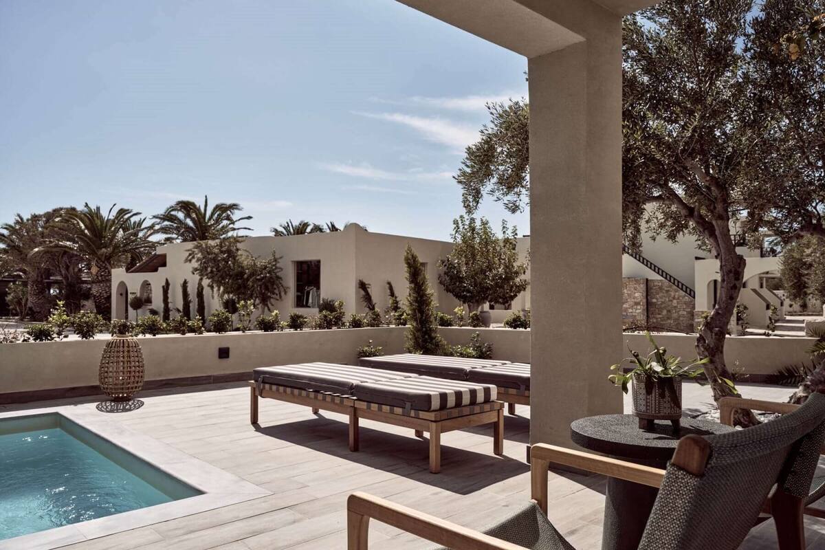 A poolside area with lounge chairs, a small table, and a decorative vase.