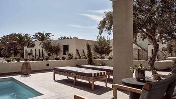 A poolside area with lounge chairs, a small table, and a decorative vase.