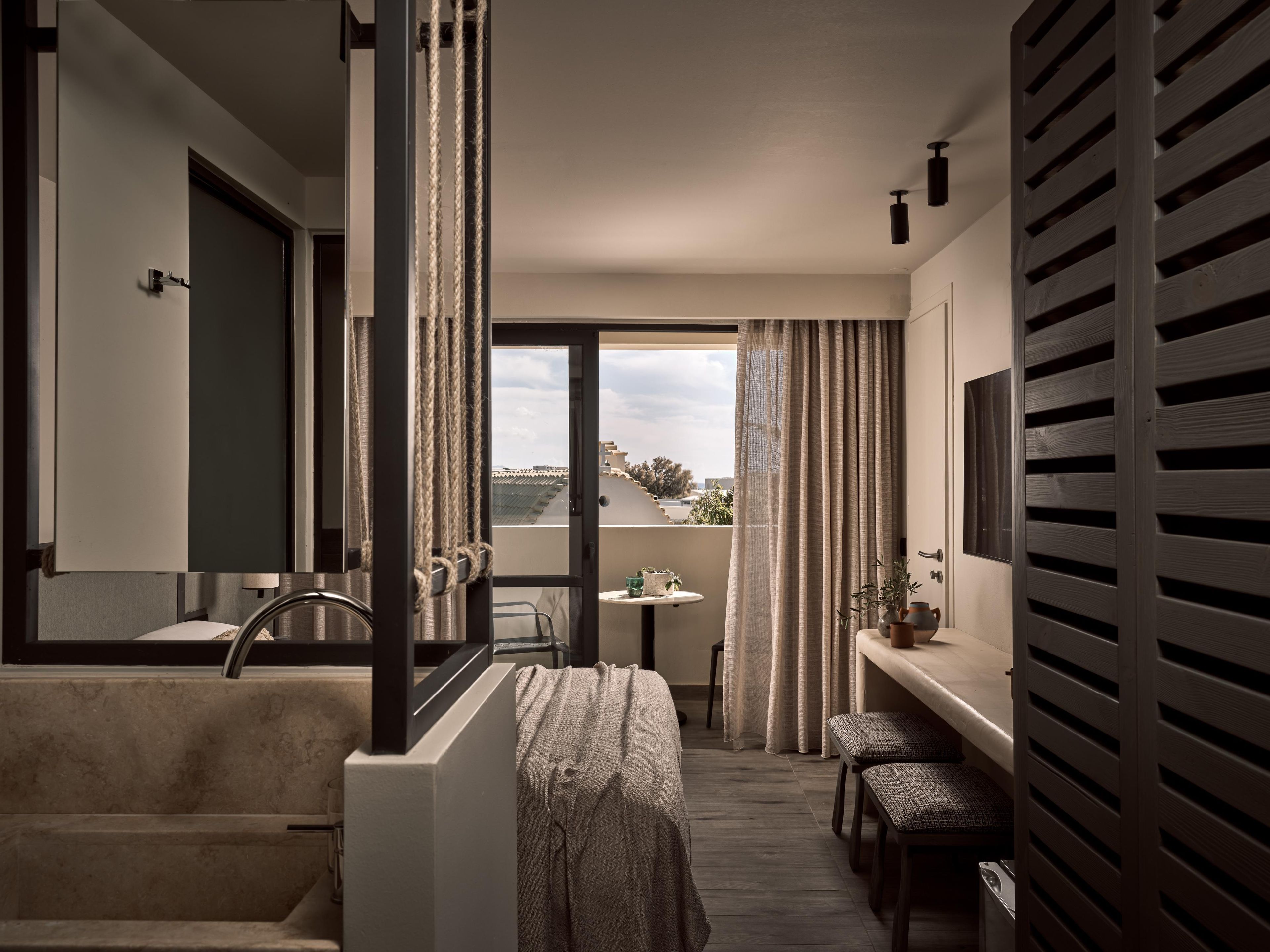 Un baño moderno con una bañera, un lavabo y un inodoro. Hay una mesita con una planta y un florero. La habitación tiene vistas al exterior.