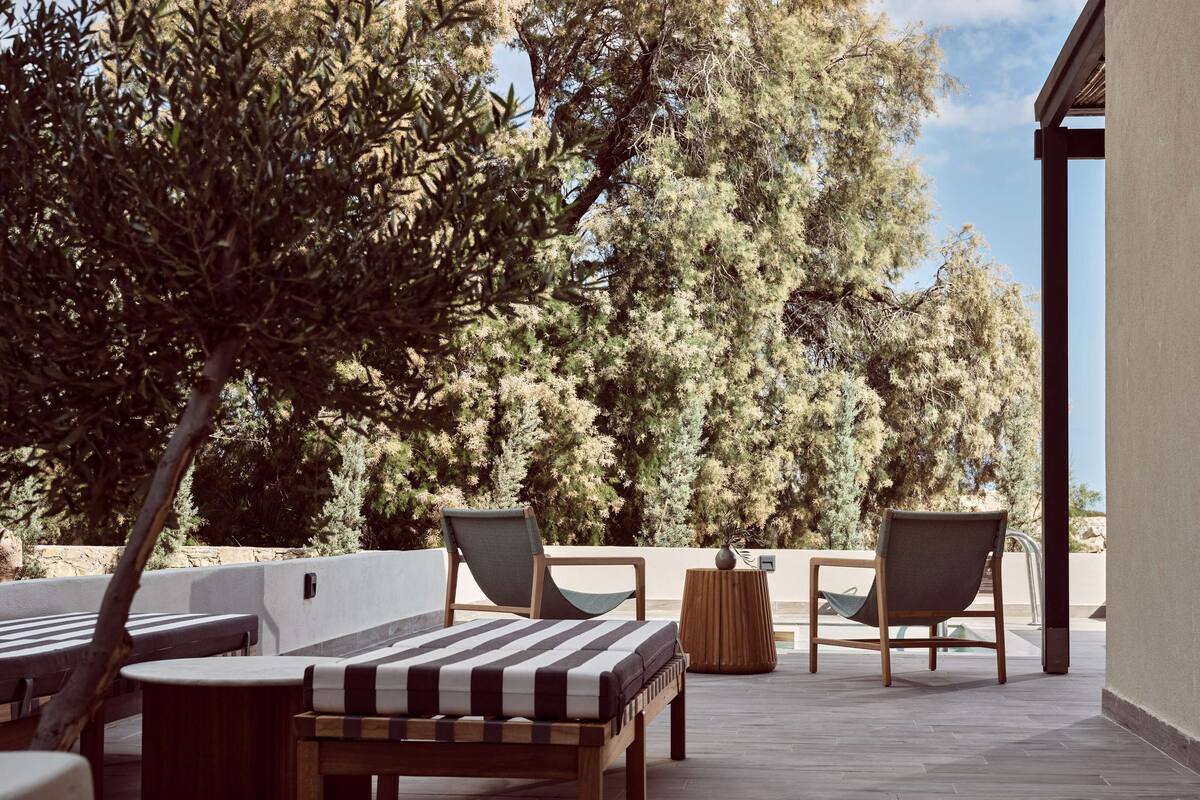 An outdoor seating area with wooden furniture, a bench, and two chairs.