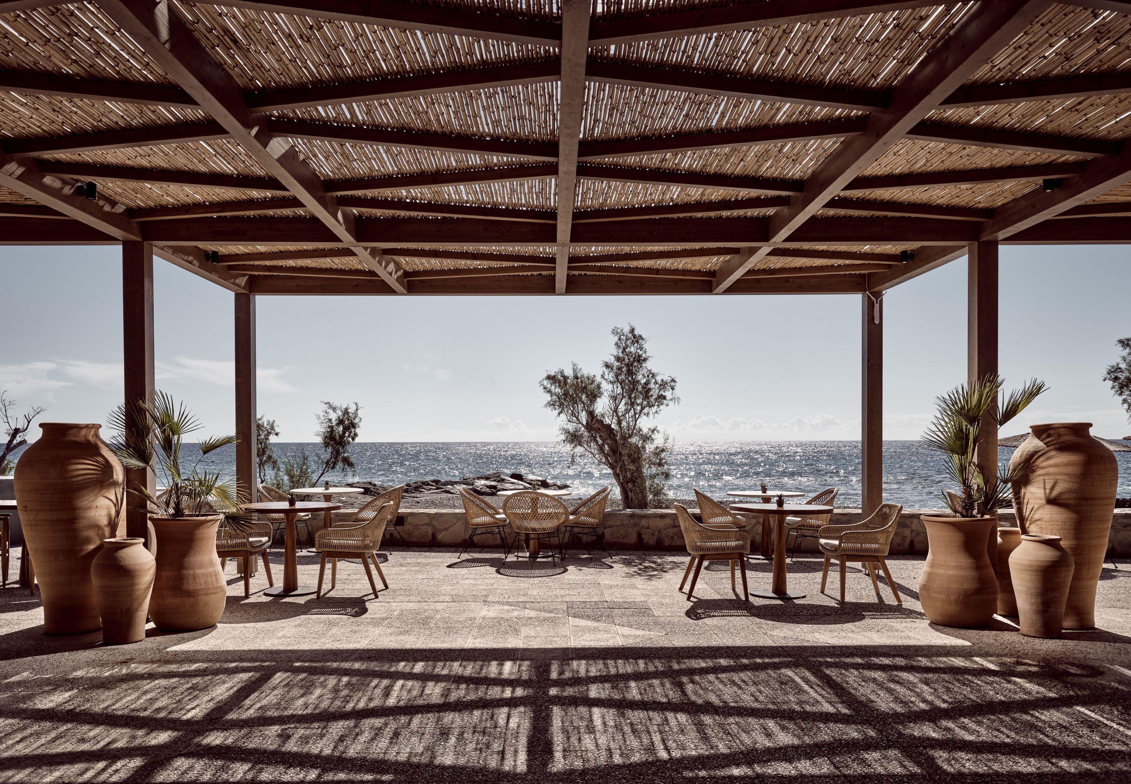 An outdoor seating area with tables and chairs, overlooking a body of water.