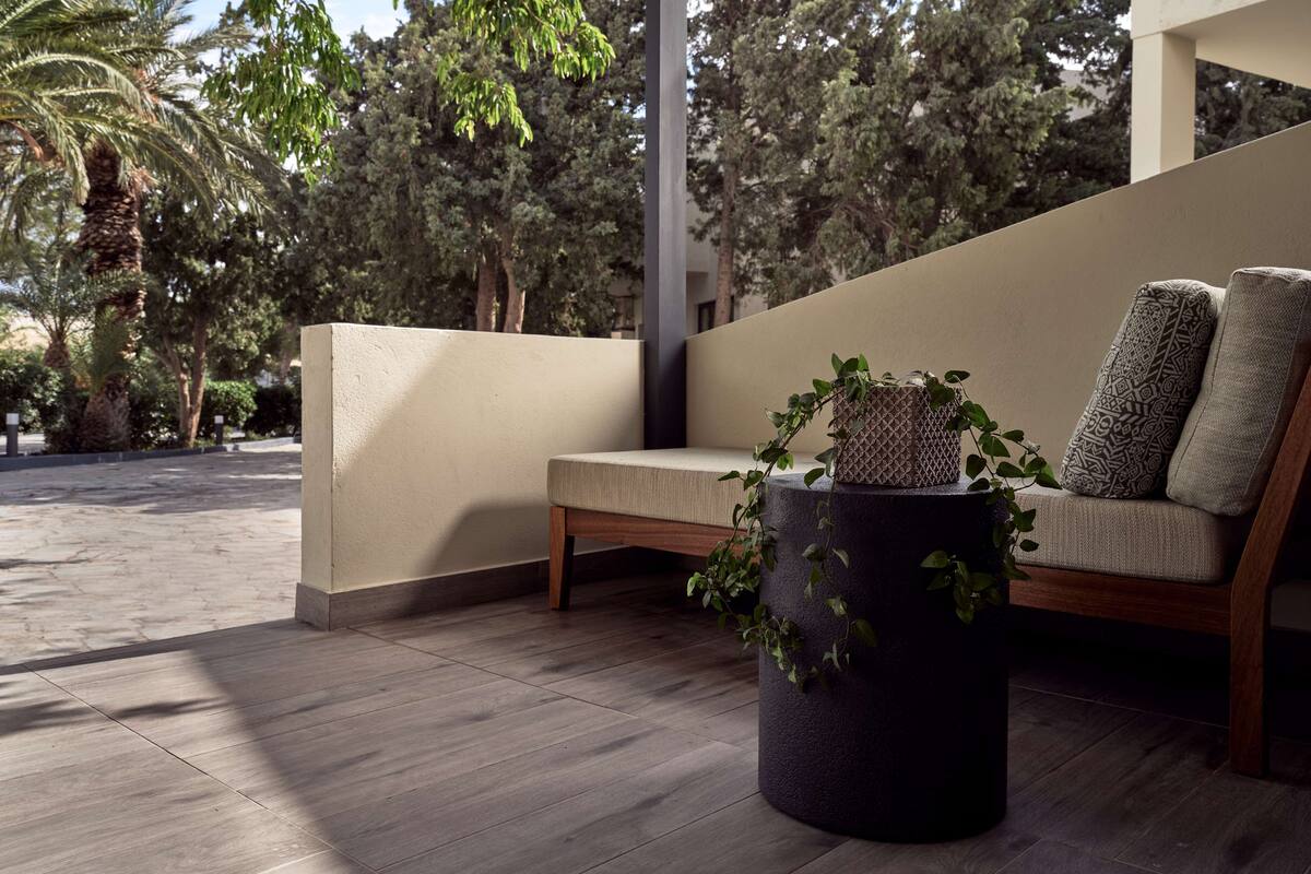 A modern outdoor seating area with a bench and a round planter with a plant.