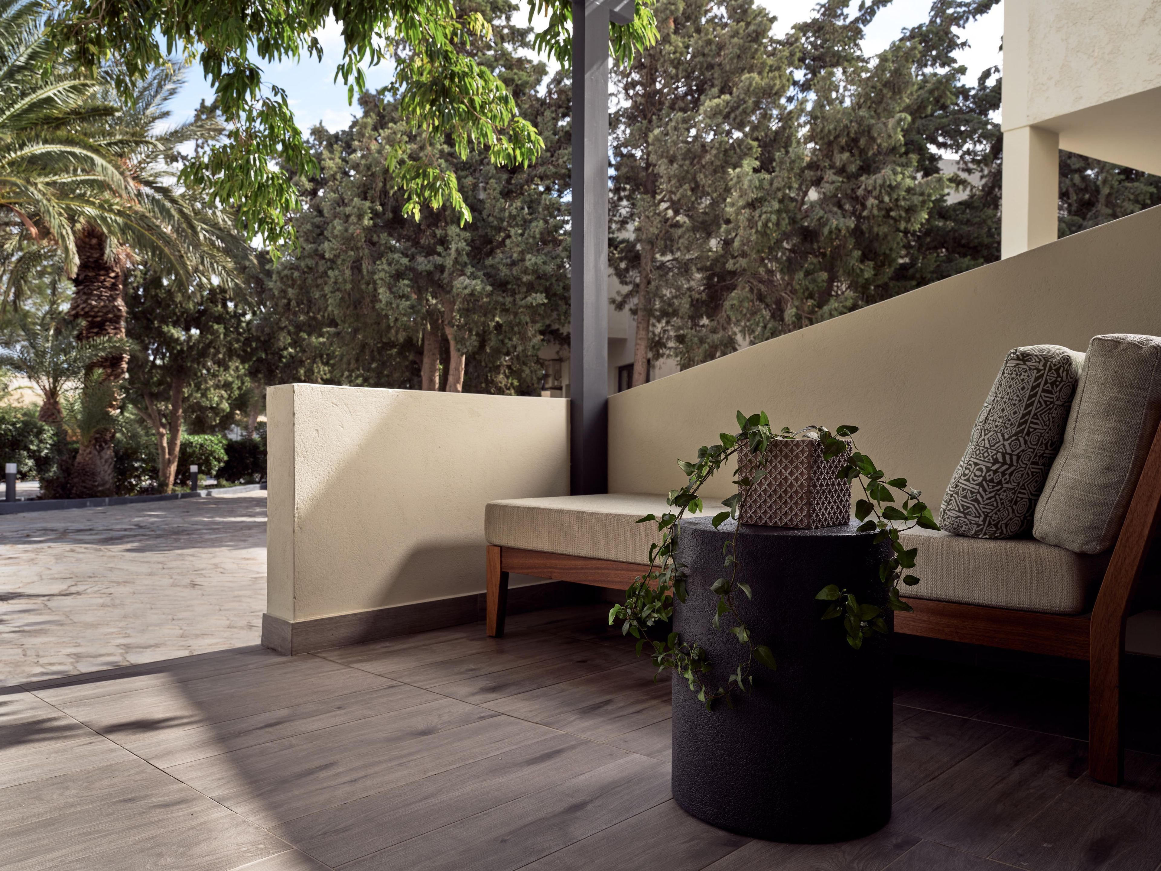 An outdoor seating area with a bench, a potted plant, and a wall.