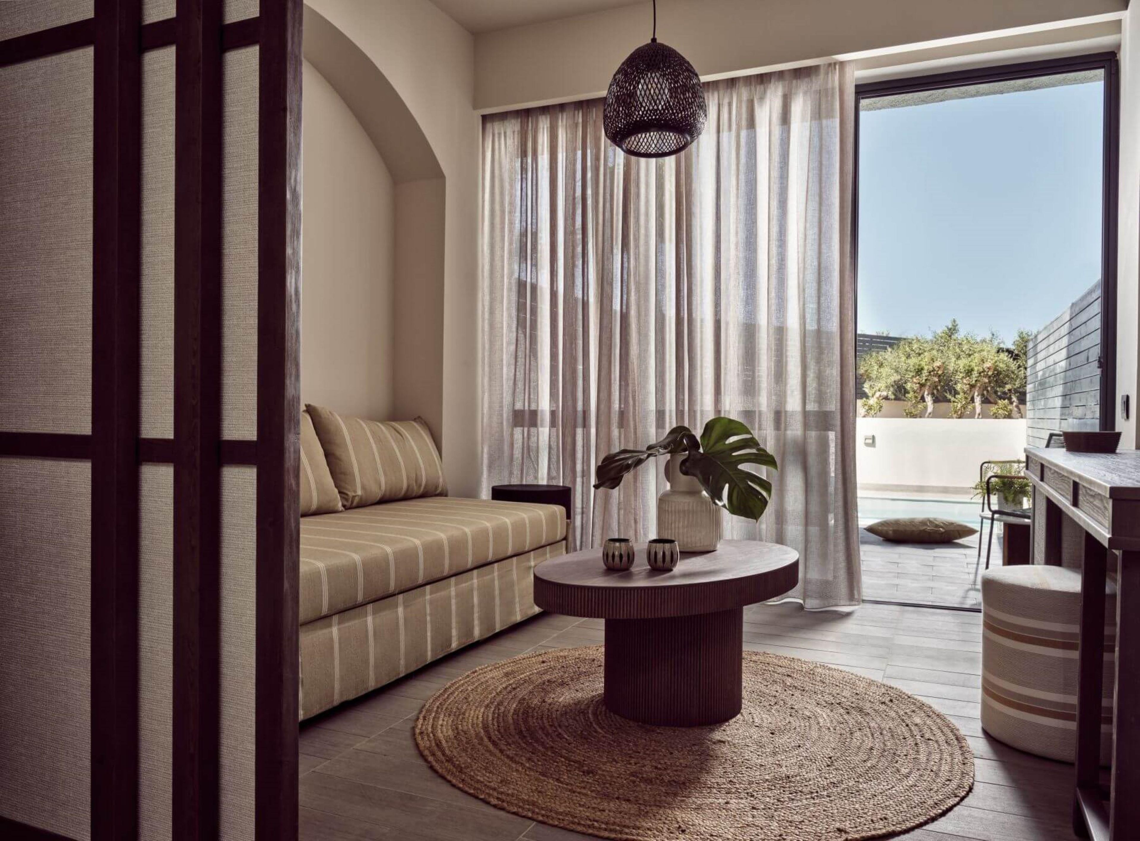 Un salon moderne avec un canapé, une table basse ronde et une vue sur l’extérieur.