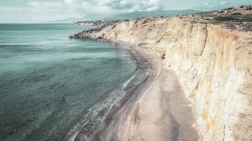 En la playa, playa de arena negra, camastros y sombrillas