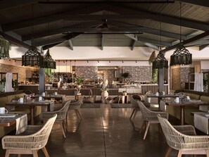 A spacious outdoor dining area with wicker furniture and hanging lights. - Numo Ierapetra Beach Resort Crete, Curio Collection Hilton (Ierapetra)