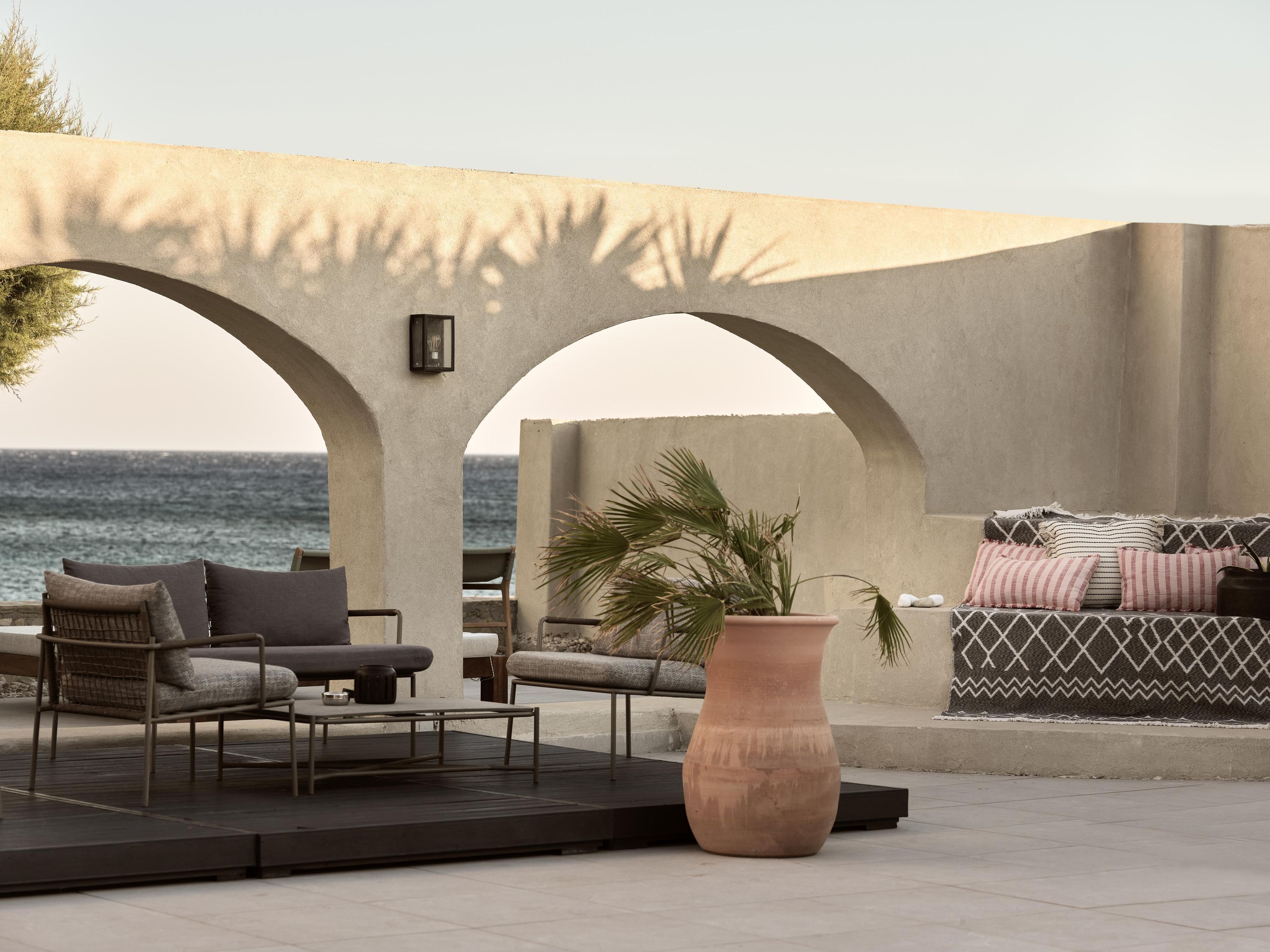 Una terraza con una zona de estar, una planta grande en maceta y vistas al mar.